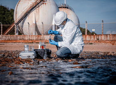 Scientist collecting water sample near tanks