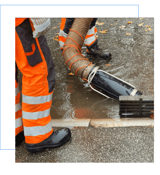 Workers managing floodwater with a large hose