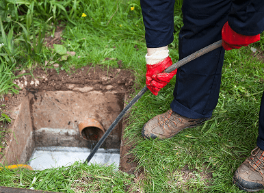 Hands cleaning blocked outdoor sewer
